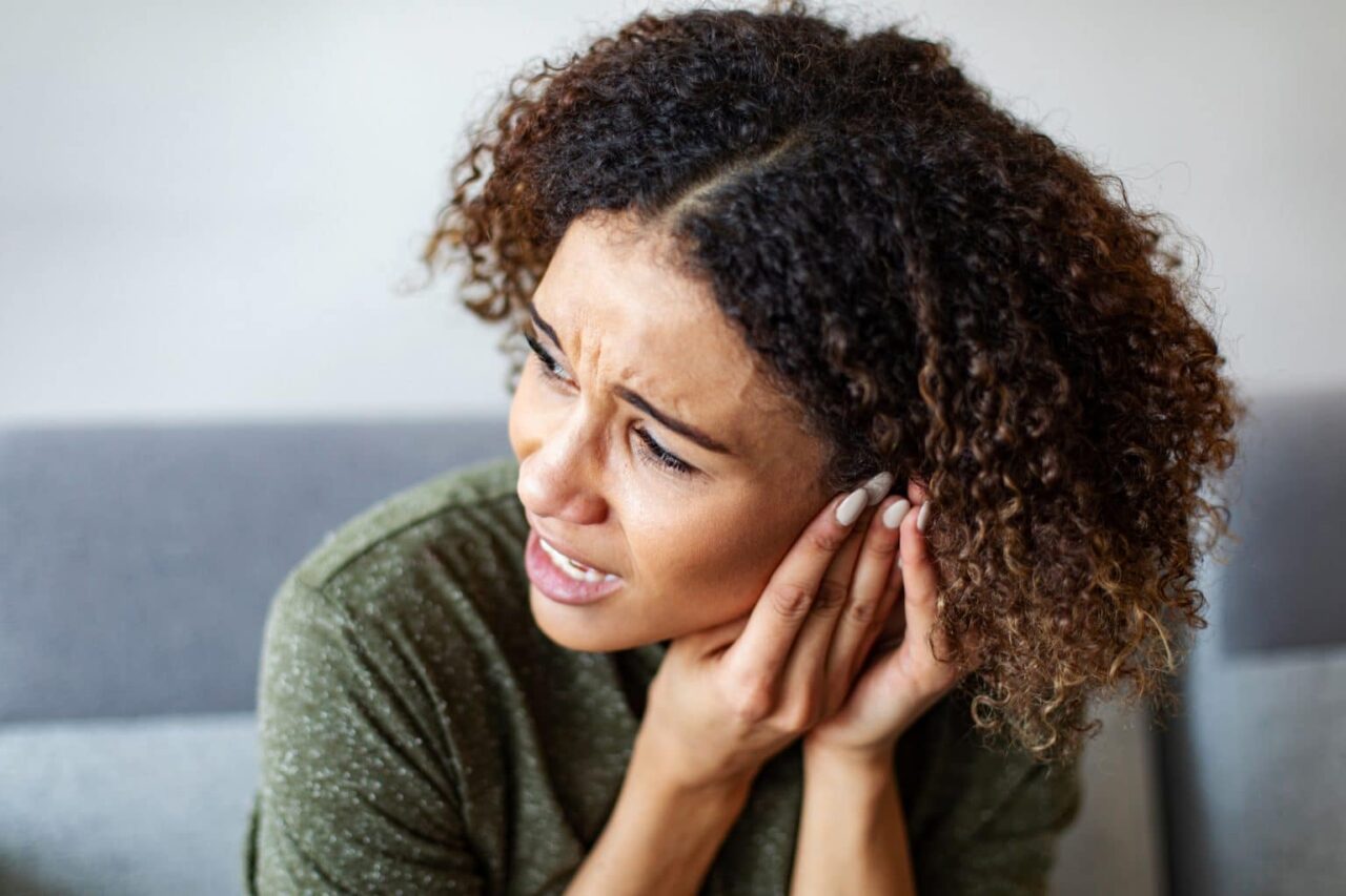 Woman experiencing ear pain.