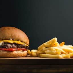 A cheeseburger and fries against a black background.