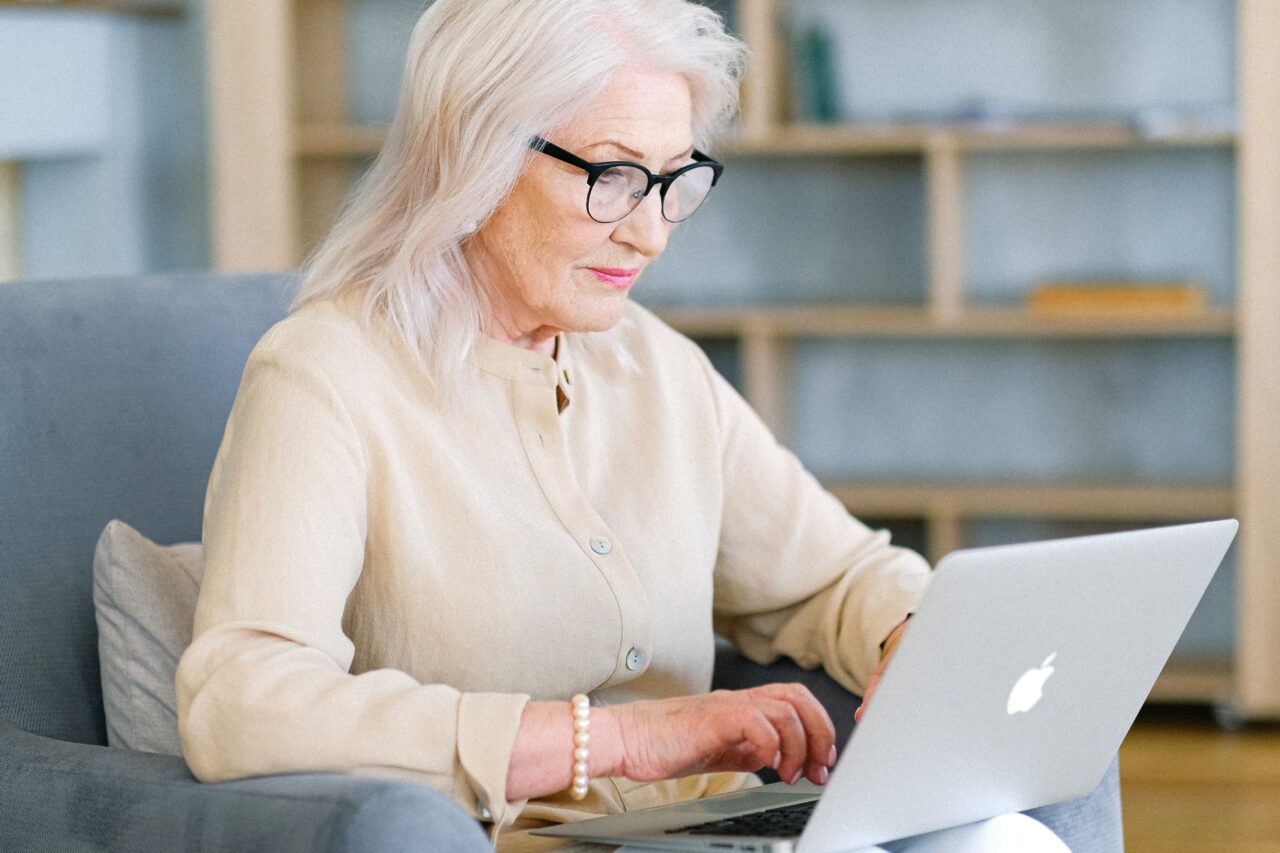 Older woman in glasses working on her laptop.
